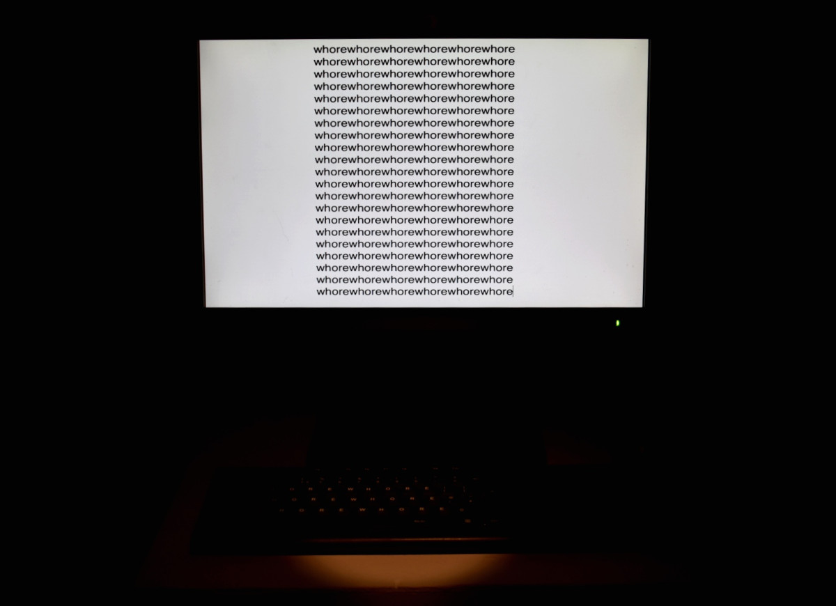 Video piece illustrating the word 'whore' being repeatedly typed on the screen